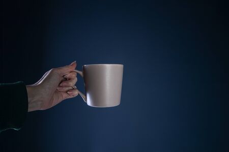 female hand with a cup, on a blue background.の写真素材