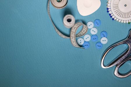 Sewing accessories and fabric on a blue background. Sewing threads, needles, pins, fabric.