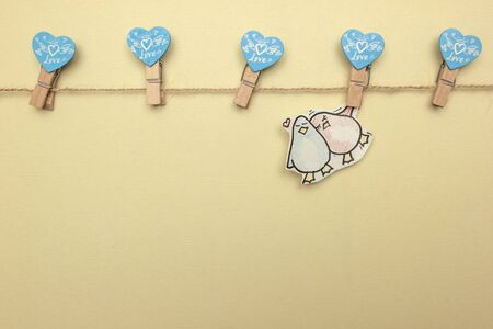 A small drawing of a cute couple penguin in love hanging on a clothesline On a pink background. valentines day conceptの写真素材