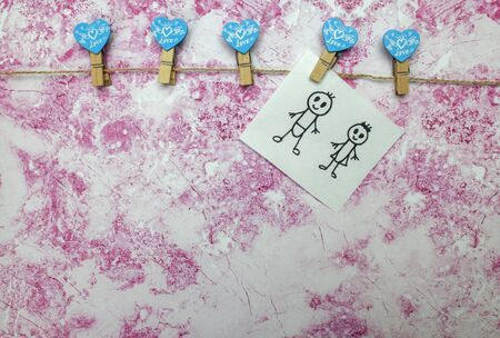 A small drawing of a cute couple in love hanging on a clothesline On a white and pink background....