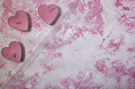 Candles in the shape of hearts on a pink and white backgroundの写真素材