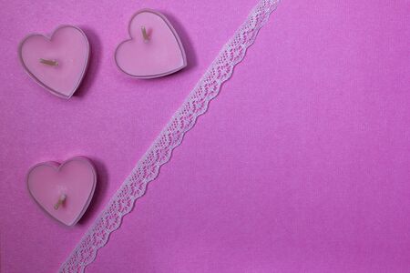 Candles in the shape of hearts on a pink backgroundの写真素材