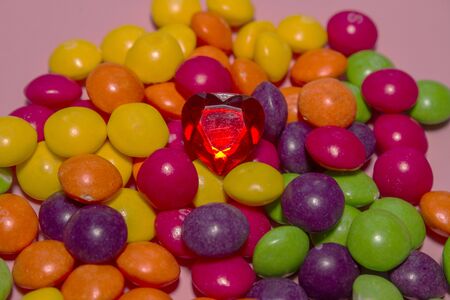 a pile of colorful Skills sweets with a red heart on top. Pink backgroundの写真素材