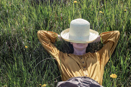 Agriculture farmer rest after day work. Worker in rural farm. farmer relax on grass. Ecology concept. Greenfield in summer. Countrygirl on green meadow.の写真素材