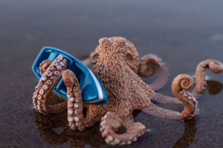 a large toy octopus sits in the water and holds a boat with tentaclesの写真素材