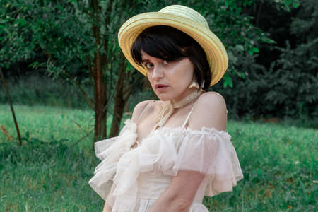 girl in white dress and straw hat on a walk in natureの写真素材