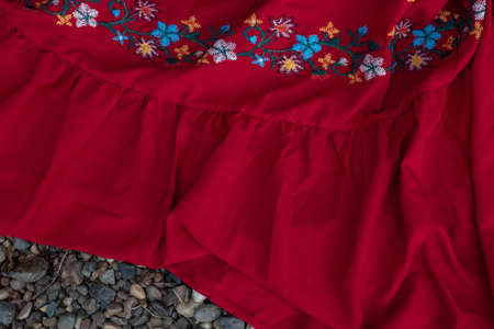 red fabric with embroidery on sea pebblesの写真素材