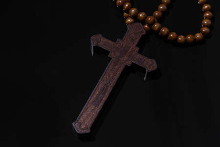 Wooden christian cross necklace on black backgroundの写真素材