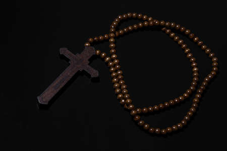 Wooden christian cross necklace on black background
