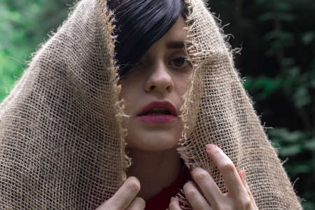 Girl with black hair hiding in sackcloth, concept photoの写真素材