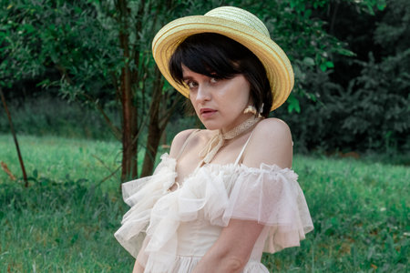 girl in white dress and straw hat on a walk in natureの写真素材