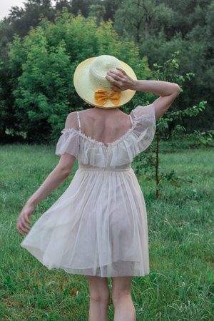 girl in white dress and straw hat, portrait on natureの写真素材