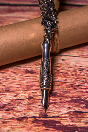 Old quill pen with old paper scroll on the dark wooden table. Letter writing. Historical atmosphereの写真素材