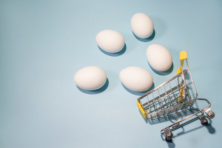 Pink easter egg in shopping cart with space on blue background, happy easter card background idea.