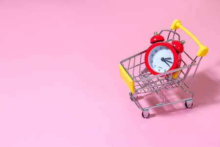 red alarm clock in supermarket trolley, concept photo of time managment, online shopping. Template mockup for greeting card your text designの写真素材