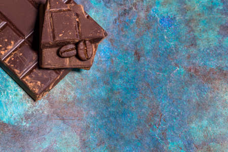Broken pieces of chocolate on blue abstract background. Top view.の写真素材