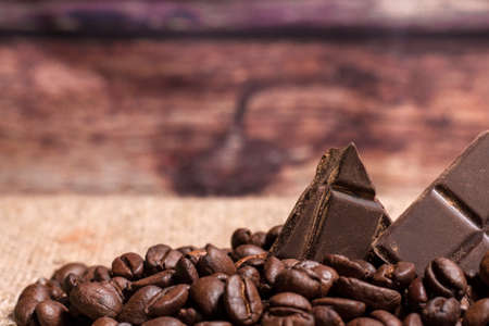 Stack of chocolate chunks with coffee beans on a wooden background, horizontal with copy spaceの写真素材