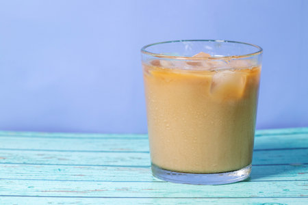 milk pour in glass of iced coffee on blue backgroundの写真素材