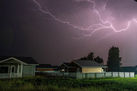 Thunderbolt over the house in the village and dark stormy sky on the background.の写真素材