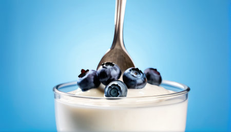 Yogurt in a glass with blueberries on a blue backgroundの素材