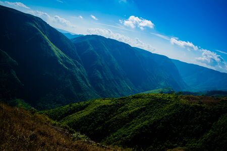 Natural view of the folded mountains and lush green valleys with clear sky and clouds of...