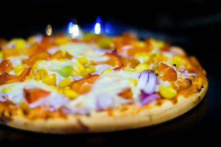 Fresh Homemade cheese pizza, with tomato, onion, corn toppings, with selective focus in lockdown.の写真素材