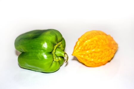 yellow bitter gourd between green capsicum with isolated background, odd one outの写真素材