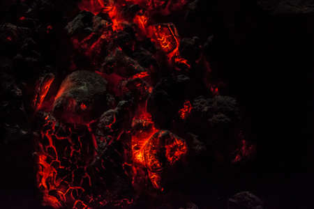 Burning and glowing charcoal close-up. Red coals with fire on a black background. Burning coals.の写真素材