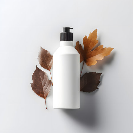 bottle of lotion sitting on a table with dry leaves around itの素材