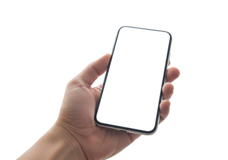 A human hand delicately grips a contemporary smartphone, its screen entirely blank and white, set against a clean, isolated white background.の素材