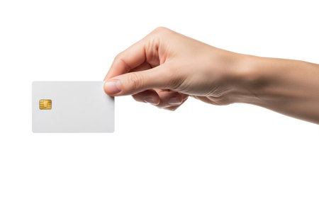 A person's hand delicately holds a plain white credit or debit card, featuring a prominent gold chip, ready for a transaction against a stark white background.の素材