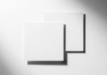 A minimalist composition featuring two blank white square cards, artfully arranged to cast subtle shadows, creating a clean and modern aesthetic for design mockups.の素材