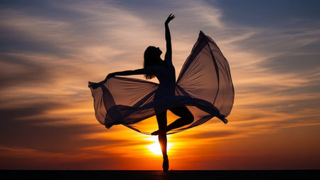 A dancer in silhouette poses gracefully with flowing fabric, set against a vibrant orange and yellow sunset.の素材