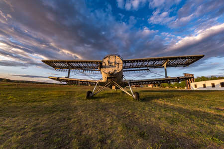 Old destroyed plane in the field in the rays of the setting sun with beautiful cloudsの写真素材