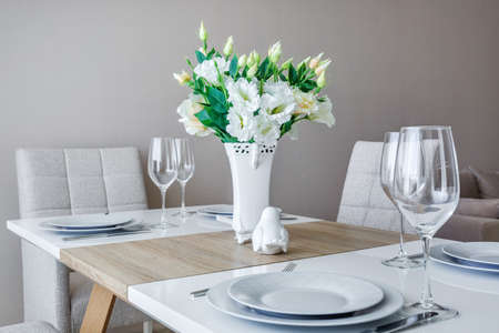 served table with a bouquet of roses in interior of modern luxure guest room in studio apartments in...