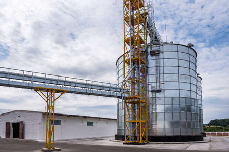 Modern Granary elevator. Silver silos on agro-processing and manufacturing plant for processing...