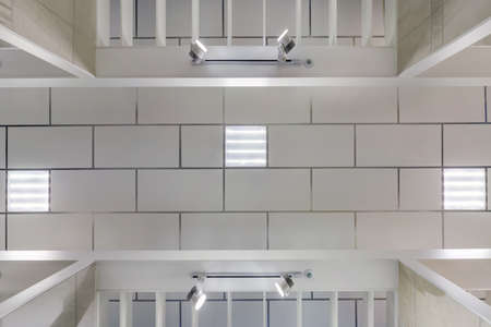 cassette suspended ceiling with square halogen spots lamps and drywall construction in empty room in...