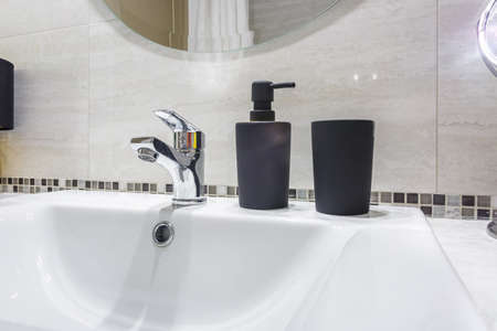 Ceramic Water tap sink with faucet with black soap and shampoo dispensers in expensive bathroom