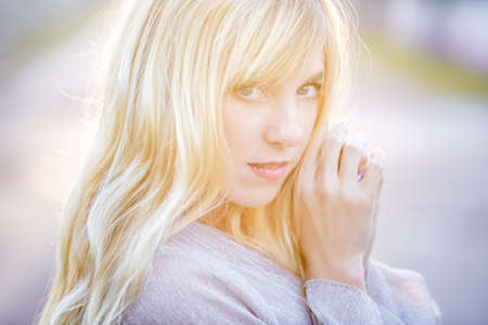 Outdoor close up portrait beautiful blonde girl with youth and skin care attractive looking at camera.の写真素材