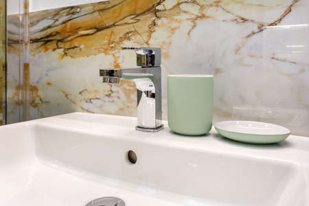 metal water tap sink with faucet with soap and shampoo dispensers in expensive bathroomの写真素材