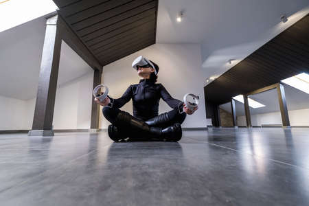 woman sitting on floor in lotus position in wireless 360 view virtual reality headset. 3D device gadget for watching movies for travel and entertainment in 3d space. Cardboard VR AR glasses.の写真素材