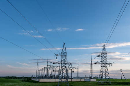 Silhouette of the high voltage electric pylon towers on the background of beautiful evening cloudsの写真素材