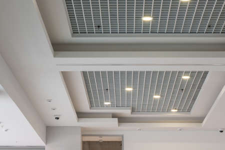 suspended and grid ceiling with halogen spots lamps and drywall construction in empty room in store...