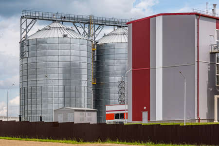 Modern Granary elevator and seed cleaning line. Silver silos on agro-processing and manufacturing plant for processing drying cleaning and storage of agricultural products, flour, cereals and grain.の写真素材