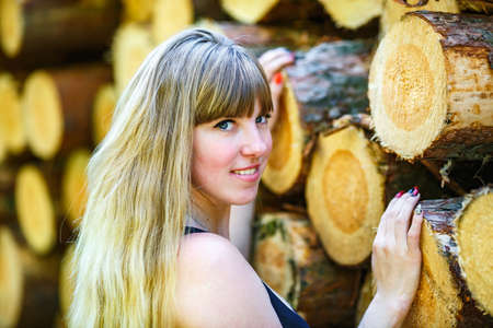 beautiful girl stands near cut logs in the forestの写真素材
