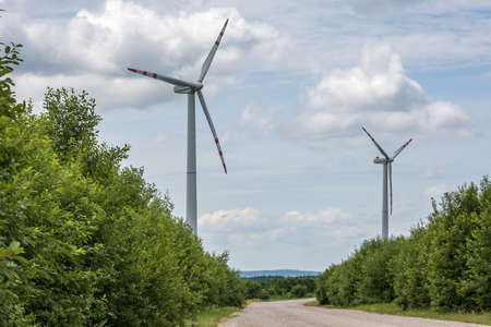 rotating blades of a windmill propeller on blue sky background. Wind power generation. Pure green...