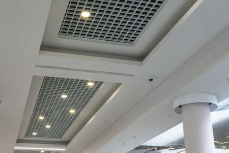 suspended and grid ceiling with halogen spots lamps and drywall construction in empty room in store...