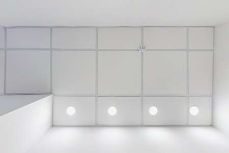 cassette suspended ceiling with square halogen spots lamps and drywall construction in empty room in...
