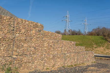 engineering structure made of stones behind metal wire netting to strengthen the river bank near the...
