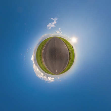 green tiny planet in blue sky with beautiful clouds. Transformation of spherical panorama 360 degrees. Spherical abstract aerial view. Curvature of space.の写真素材
